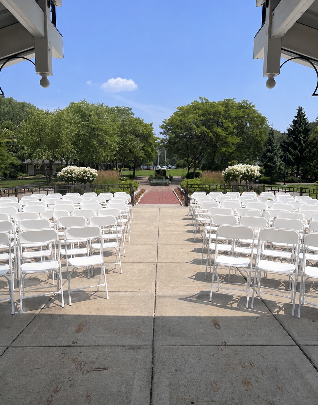 Rows of white folding chairs lining a center aisle at an outdoor ceremony