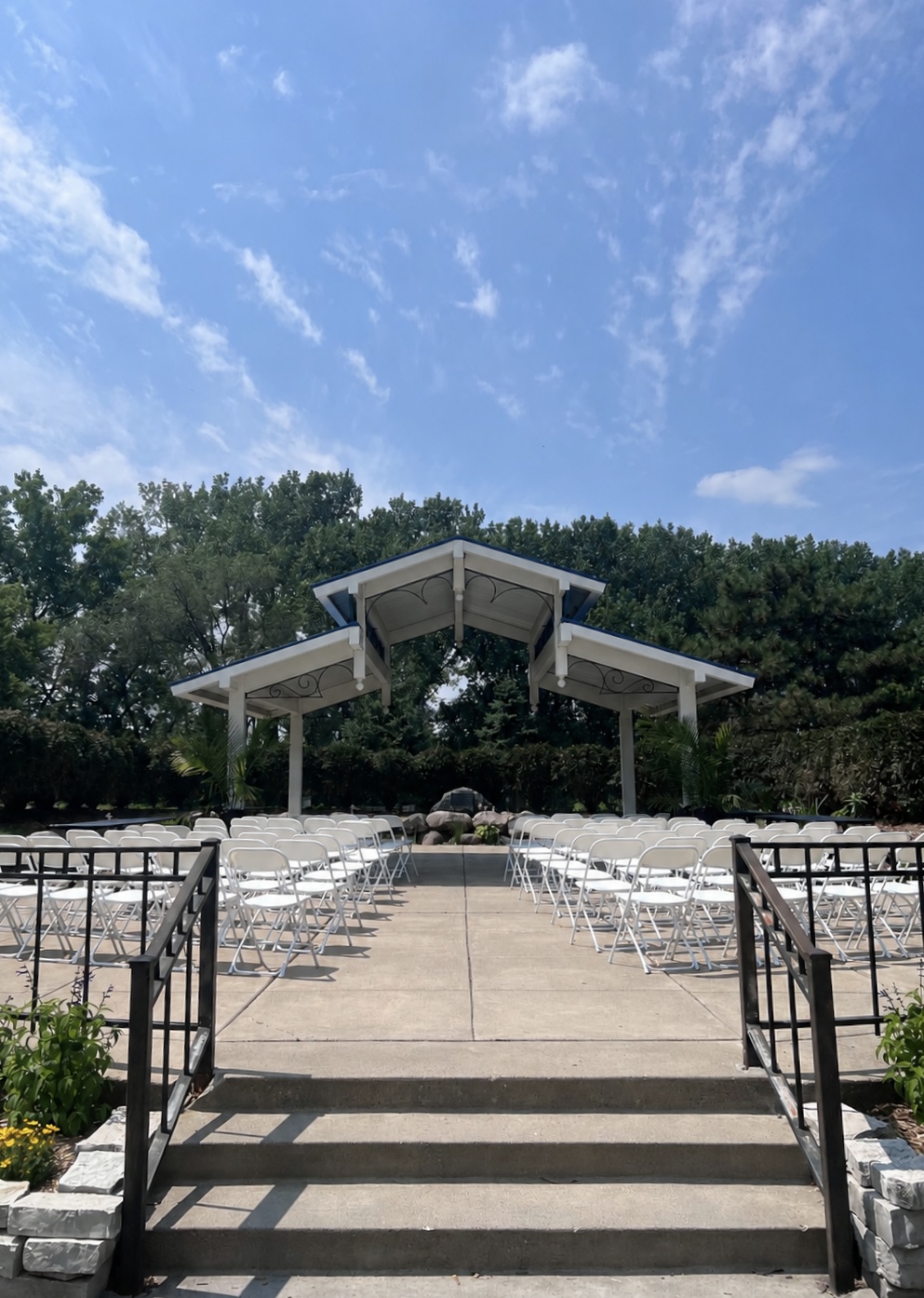 Park pavilion ceremony with white folding chairs set on the lawn
