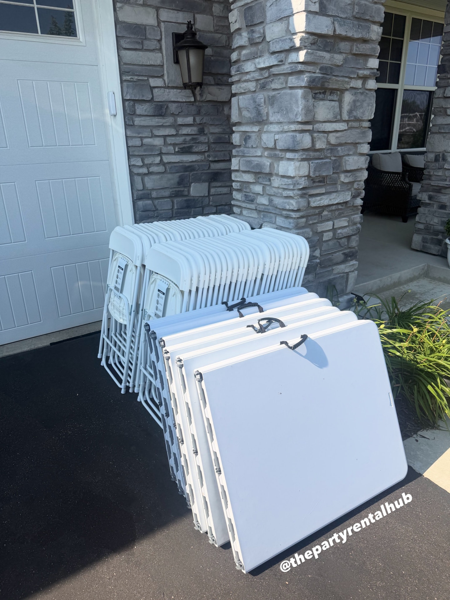 Folding tables and white chairs delivered at a stone-front entry