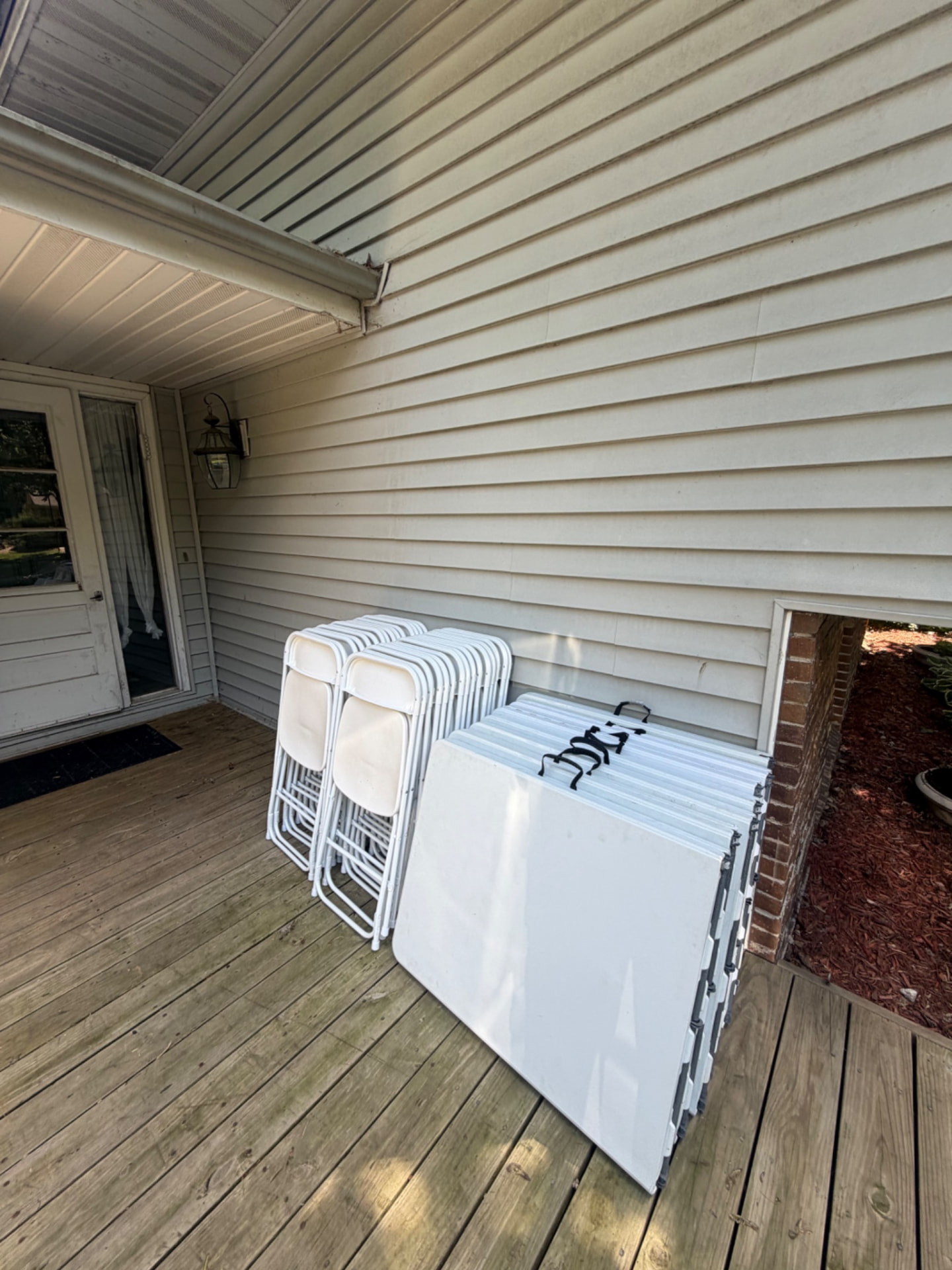 Folding tables and white chairs neatly set on a home's front porch