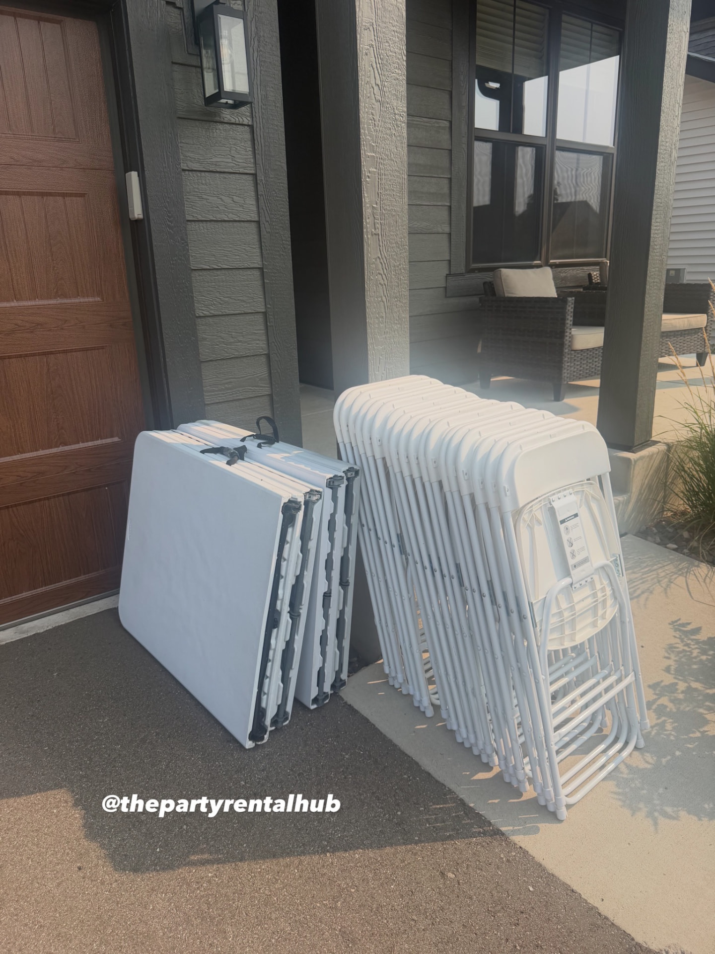 Folding table and stacked white chairs delivered to a front entry